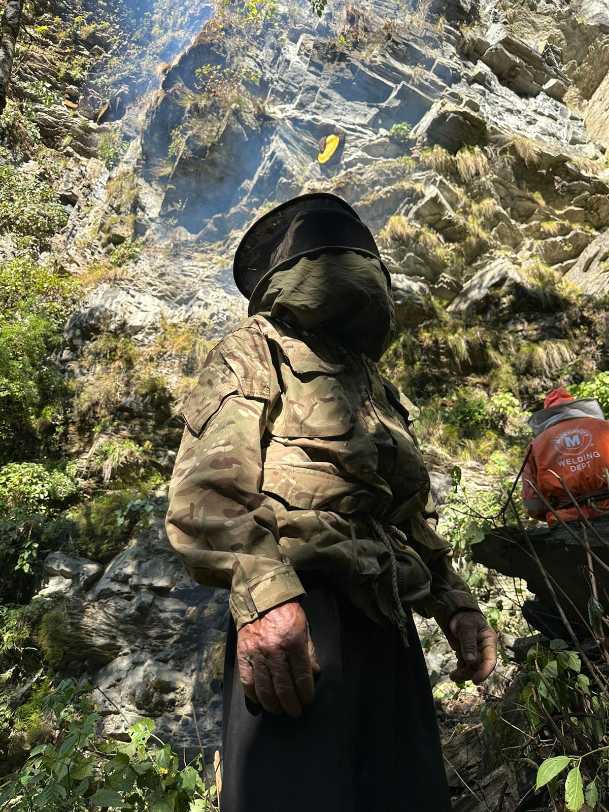 The Courageous 

A seasoned honey hunter, hands rough and strong, stands ready. His mask hides a determined gaze fixed on a massive honeycomb clinging to a towering cliff. Nature's treasure, a test of courage and skill.